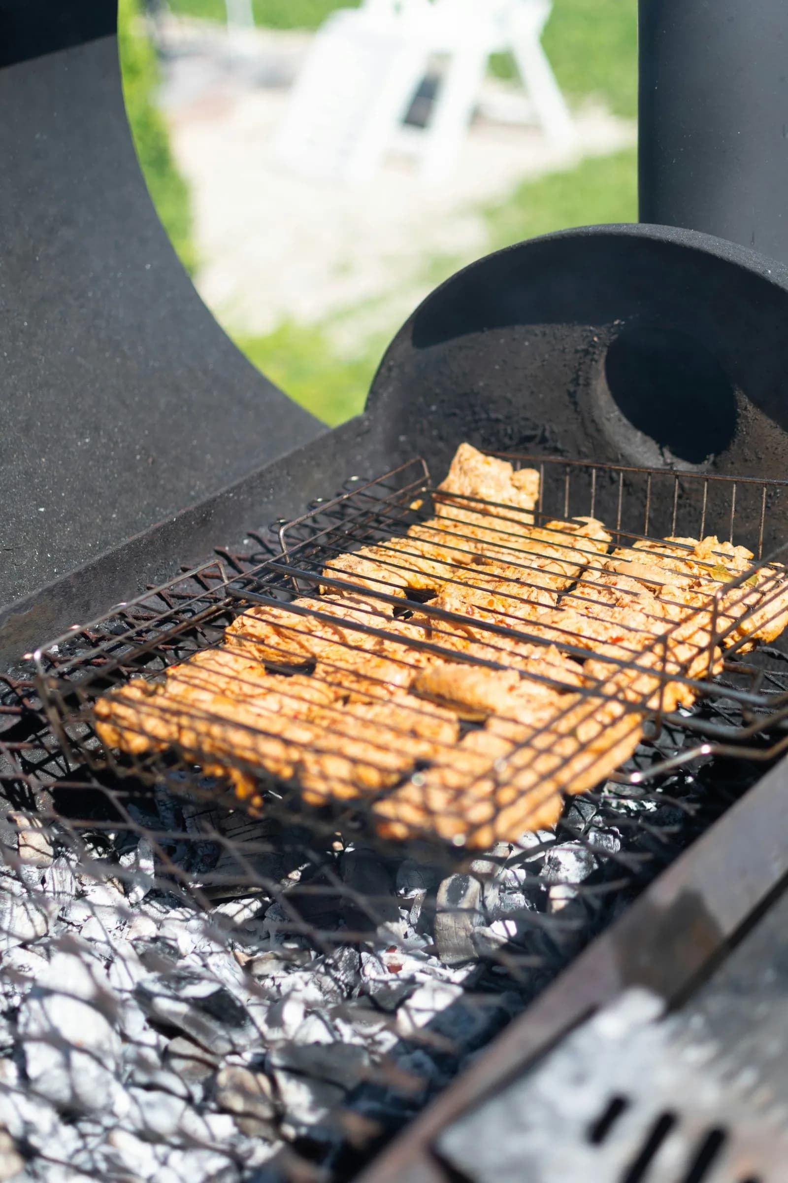 Comida cocinándose en zona indirecta sobre las brasas de una barbacoa de carbón