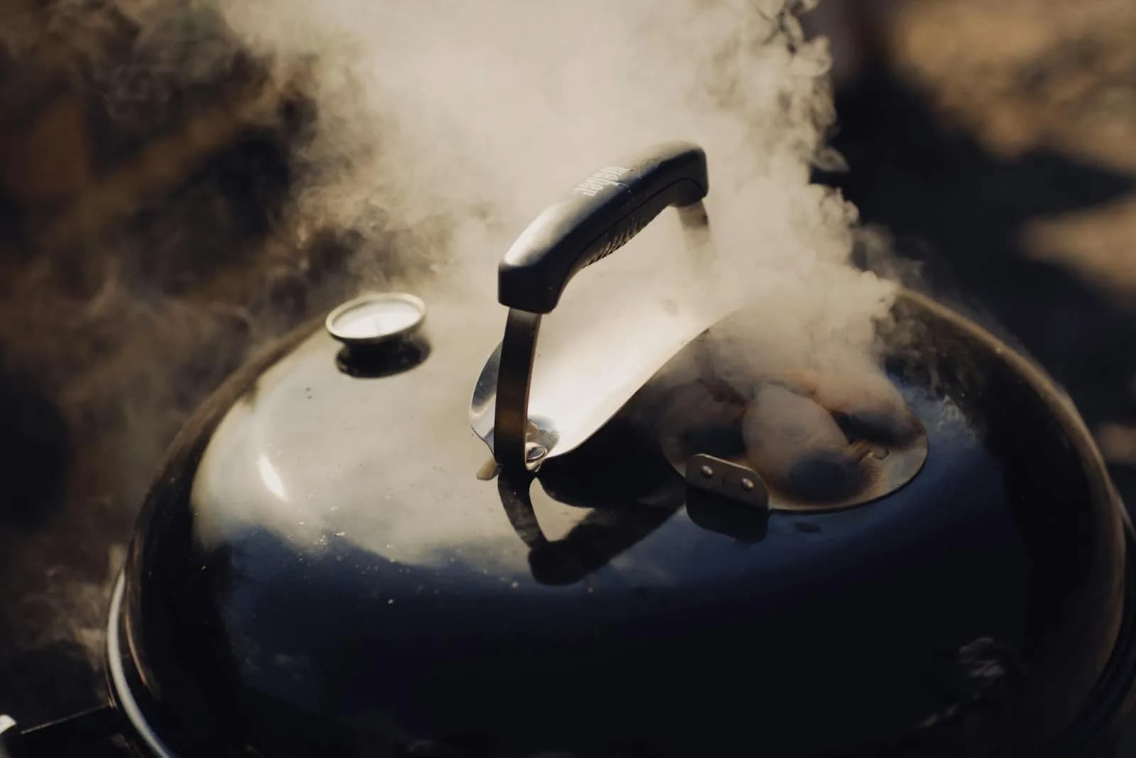 Barbacoa soltando humo a borbotones con el termómetro de cúpula