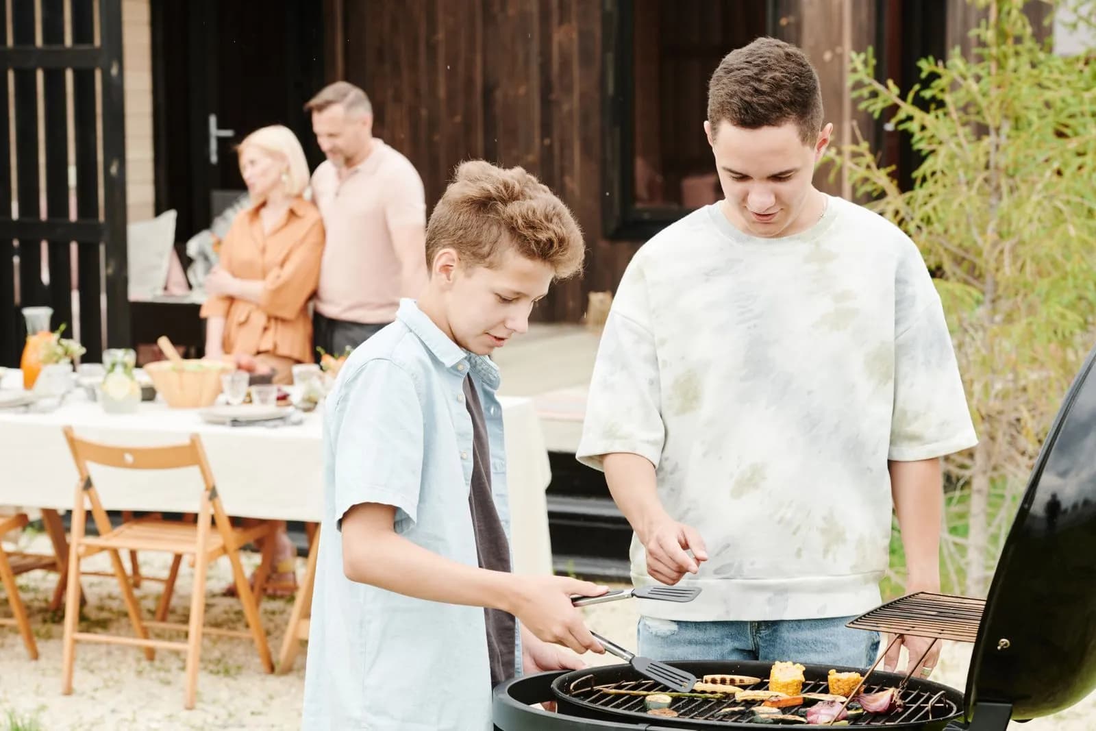 Familia reunida cocinando en una barbacoa en el jardín
