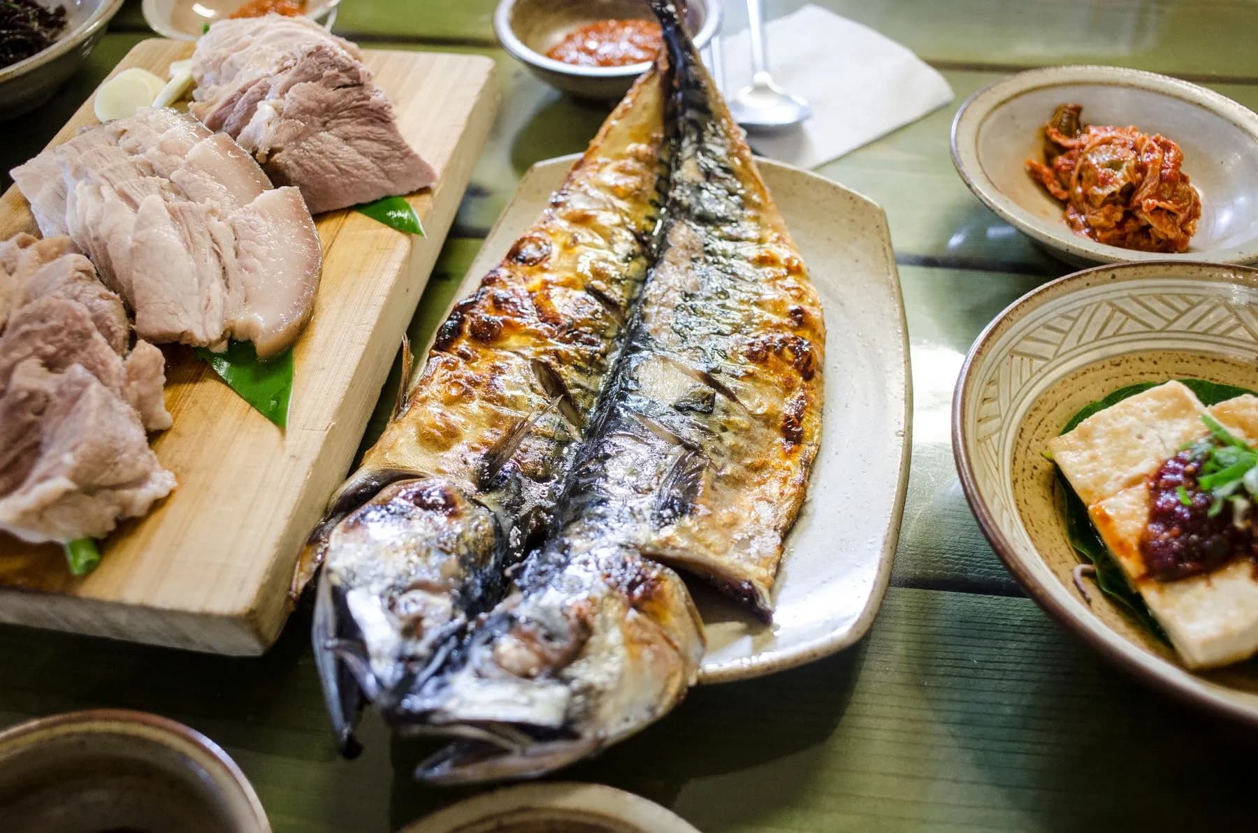 Caballa entera a la parrilla con la piel dorada y brillante, servida en una fuente