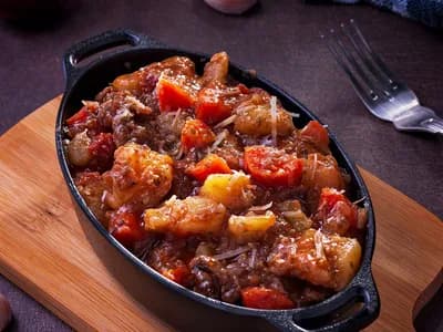 Carrilleras guisadas en salsa de vino tinto servidas en una cazuela de hierro fundido