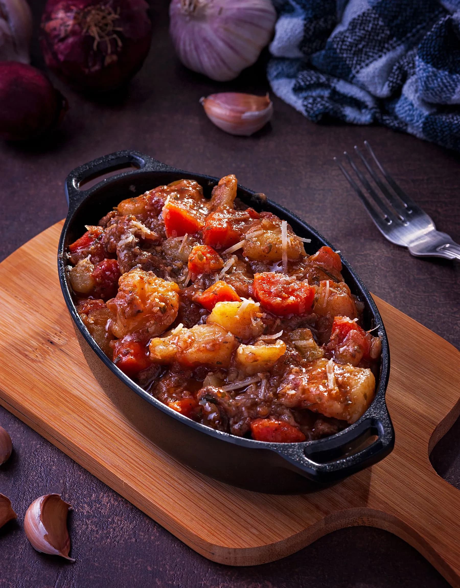 Carrilleras guisadas en salsa de vino tinto servidas en una cazuela de hierro fundido