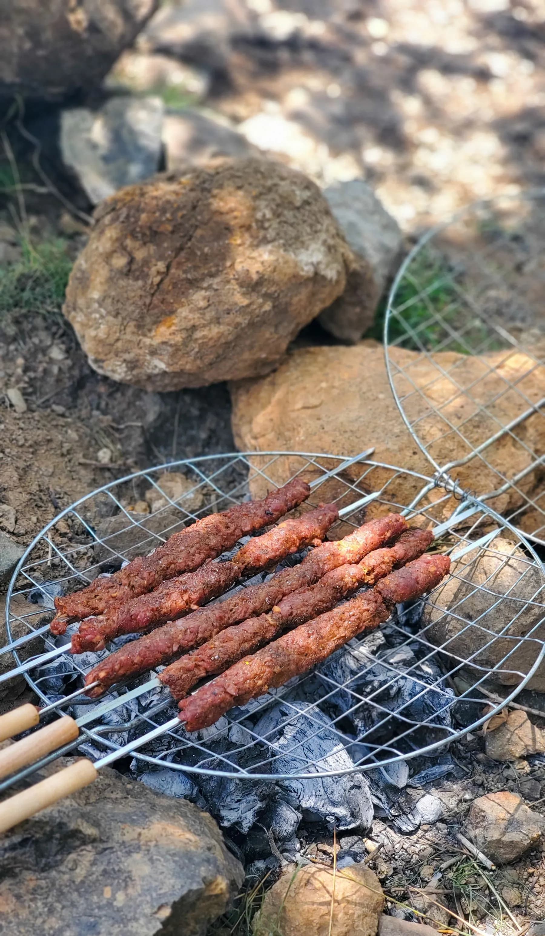 Lyulya kebab de cordero sobre la parrilla, con la costra dorada y las brasas encendidas debajo