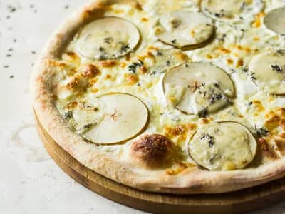 Pizza quattro formaggi blanca con gorgonzola y láminas de pera sobre mármol