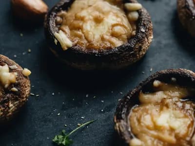 Champiñones Portobello rellenos al ajillo y gratinados con queso fundido y perejil, recién hechos.