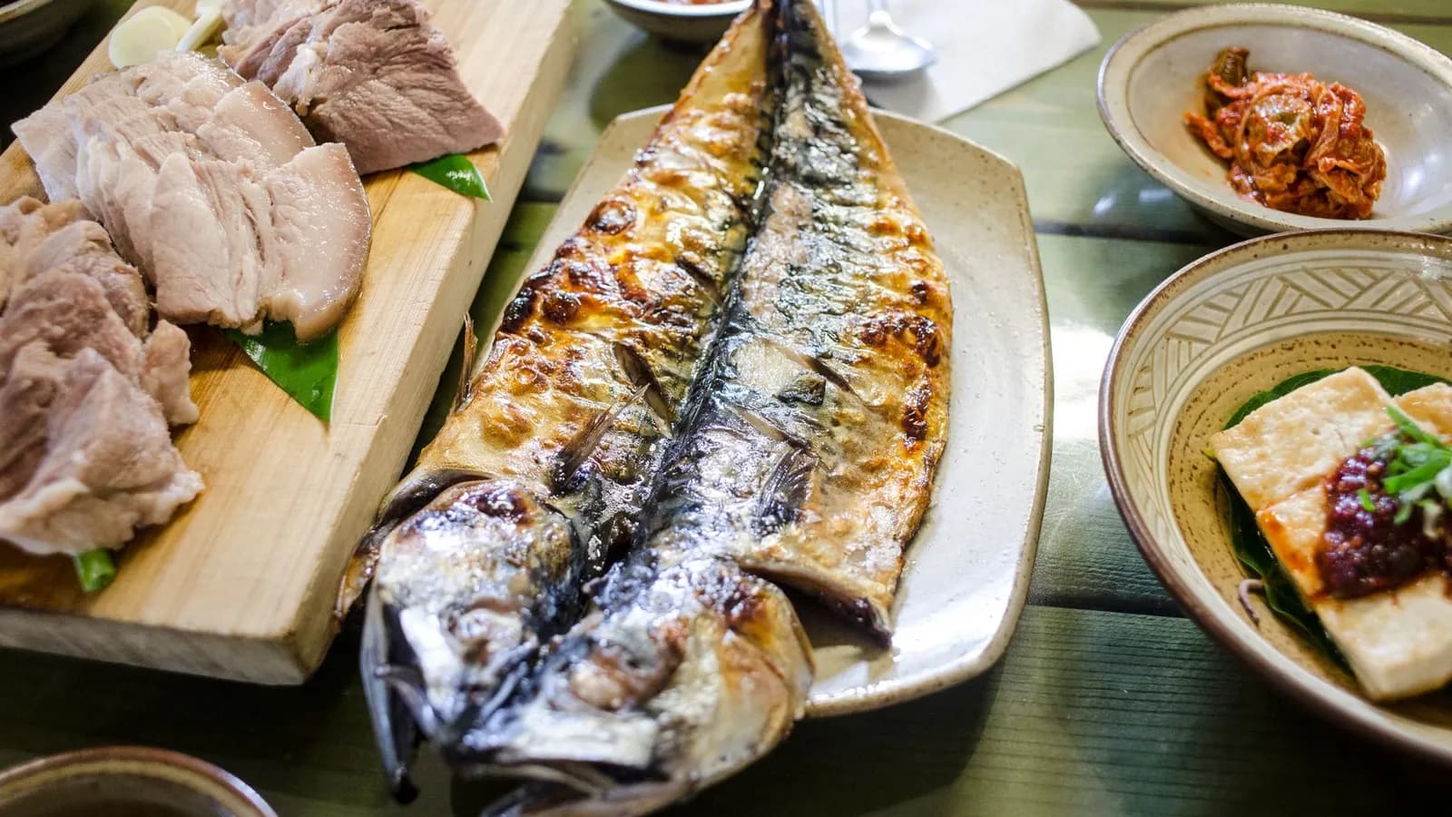 Caballa entera a la parrilla con la piel dorada y brillante, servida en una fuente