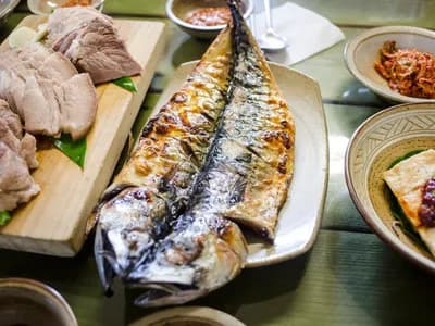 Caballa entera a la parrilla con la piel dorada y brillante, servida en una fuente