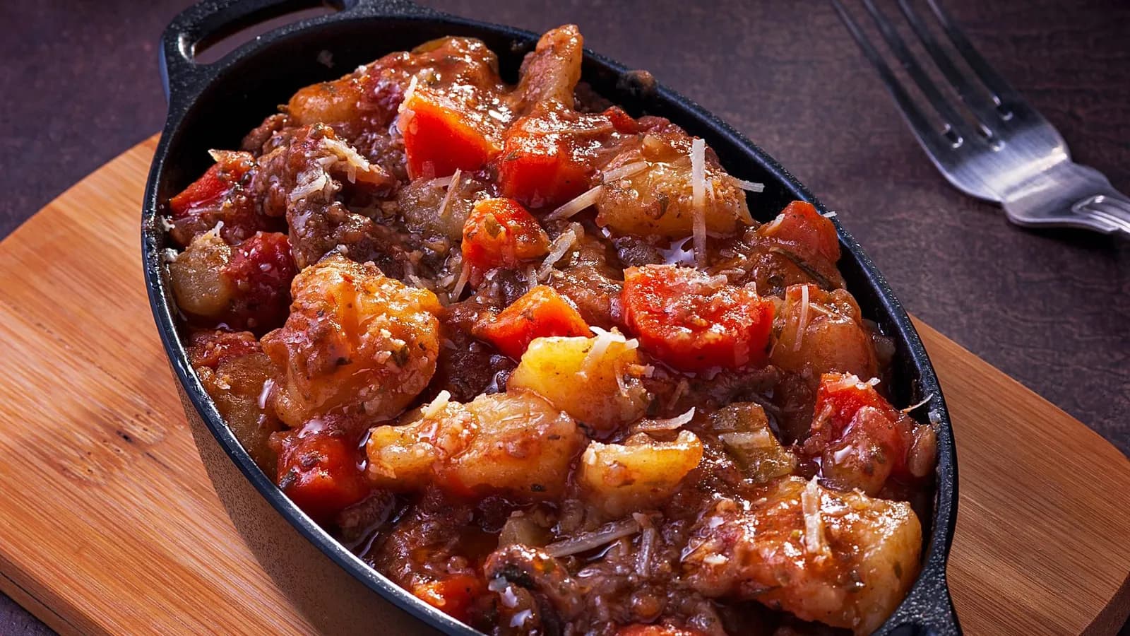 Carrilleras guisadas en salsa de vino tinto servidas en una cazuela de hierro fundido