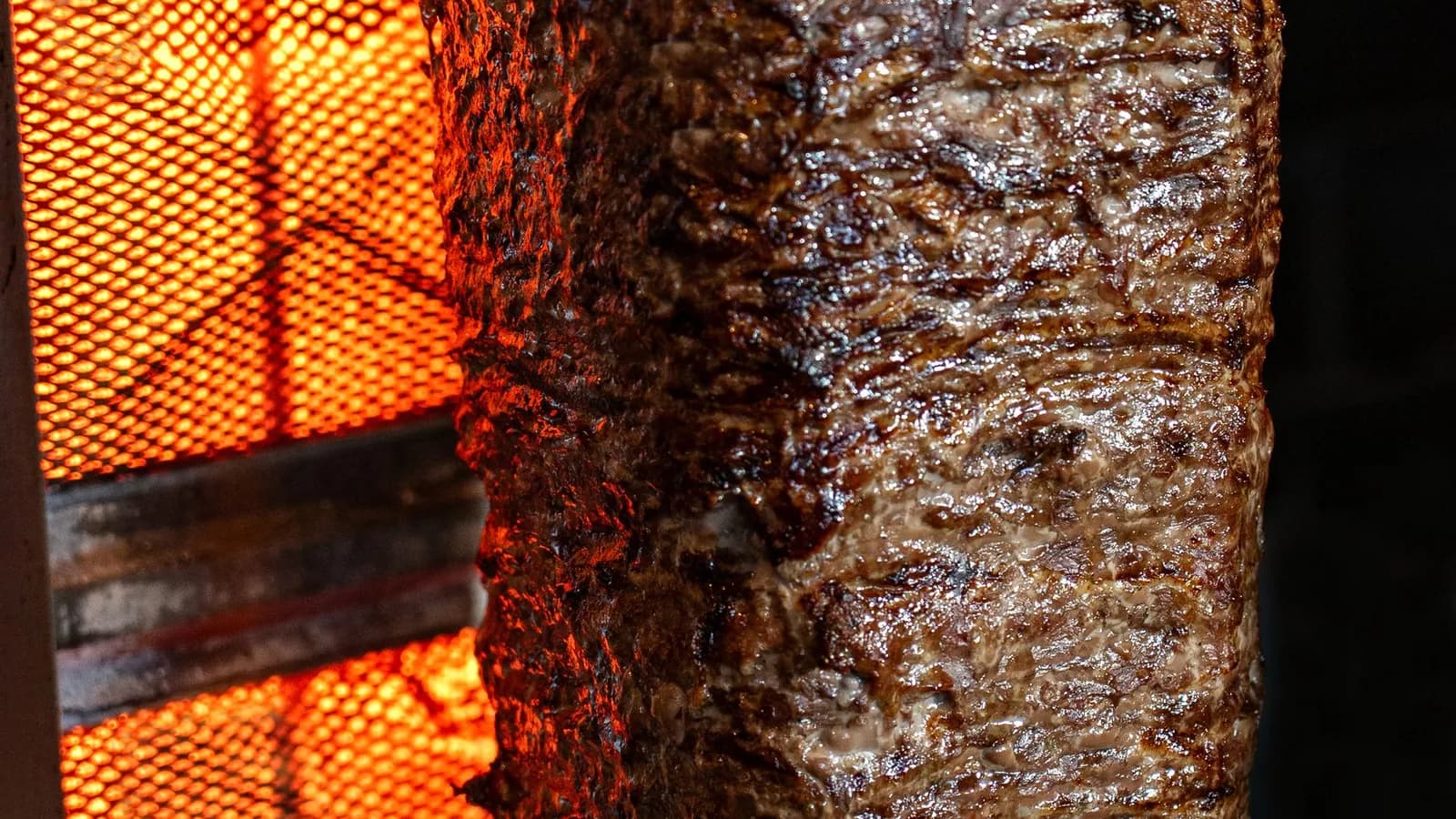 Bloque de gyros girando en el asador vertical, con la cara exterior tostada lista para cortar