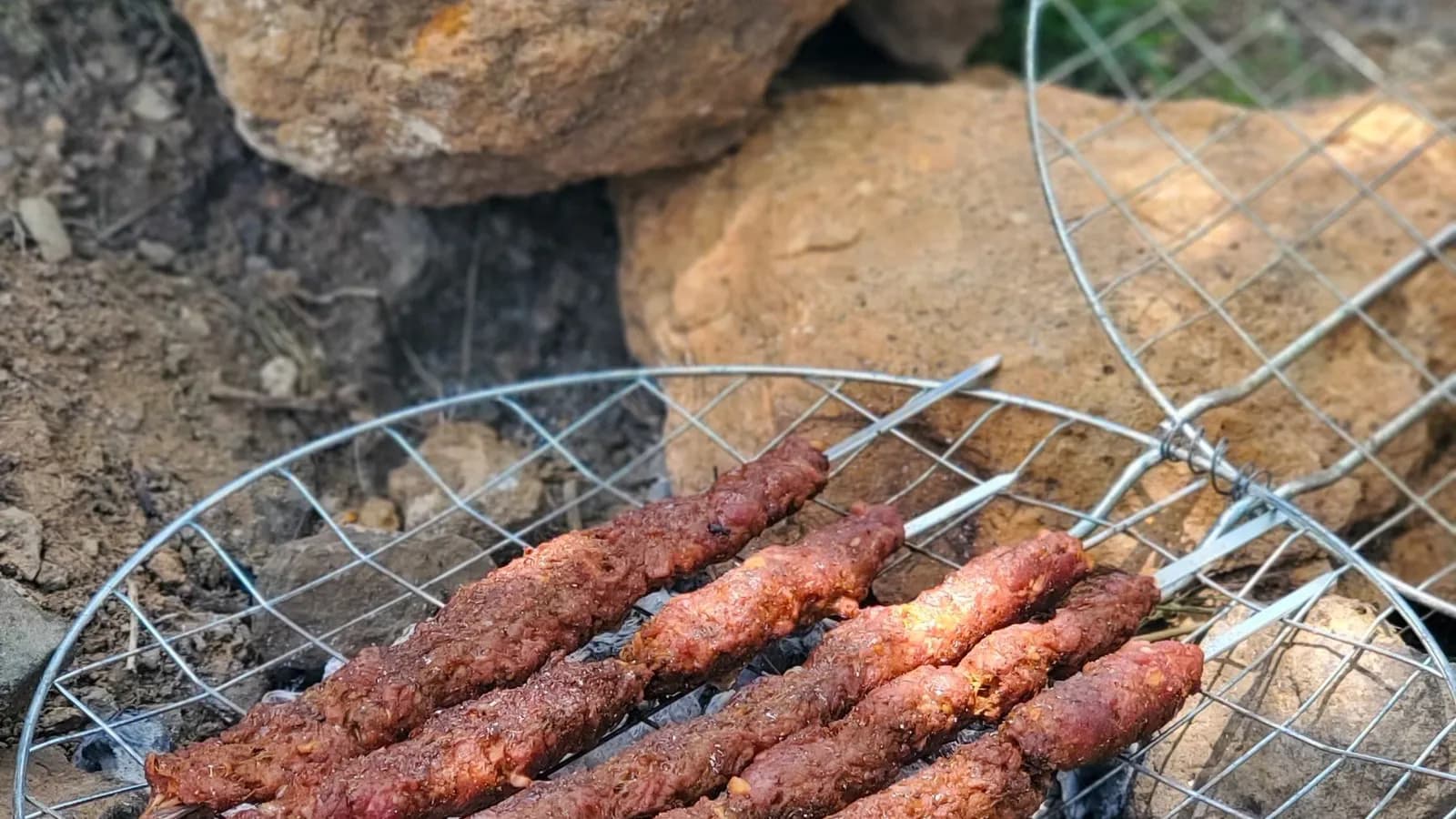 Lyulya kebab de cordero sobre la parrilla, con la costra dorada y las brasas encendidas debajo