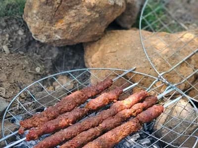 Lyulya kebab de cordero sobre la parrilla, con la costra dorada y las brasas encendidas debajo