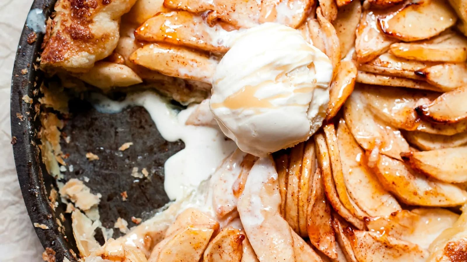Tarta tatin de manzana caramelizada en molde de hierro, con bola de helado fundiéndose